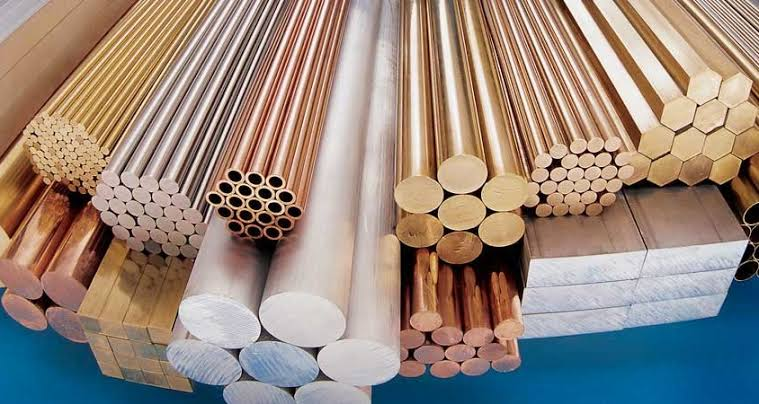 Assorted aerospace-grade carbon steel, copper, and bronze bars, tubing, and rods fanned out on a blue surface